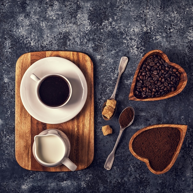 Tasse à café, grains et poudre moulue sur table en pierre.