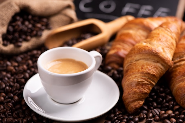 Tasse de café en gros plan sur des grains de café torréfiés foncés