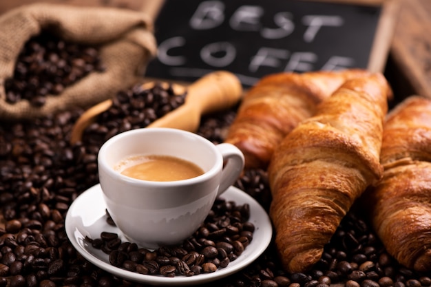 Tasse de café en gros plan sur des grains de café torréfiés foncés