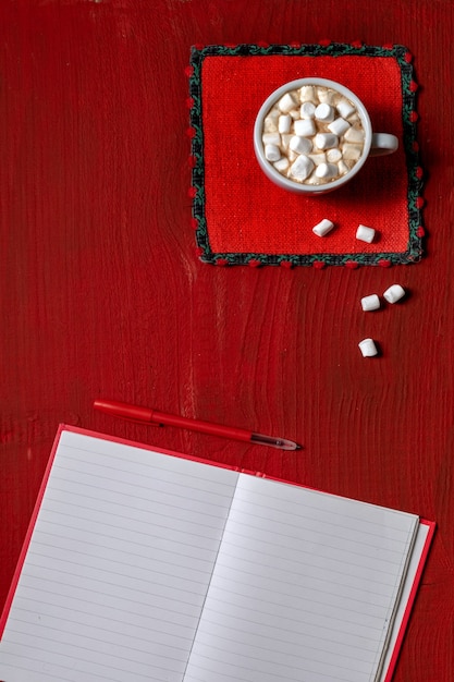 Tasse de café avec guimauve et note avec stylo sur bois rouge