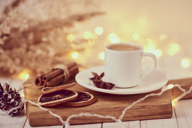 Tasse de café avec guirlandes lumineuses et décoration sur table. Concept de maison confortable