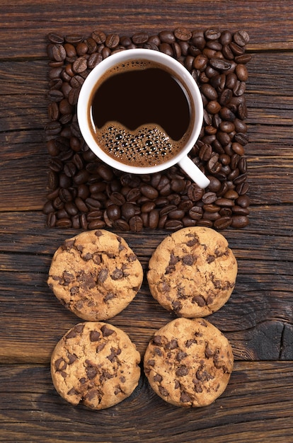 Tasse de café, haricots en forme de carré et biscuits au chocolat sur une table en bois foncé, vue de dessus