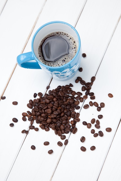 Tasse de café et haricots sur table en bois blanc