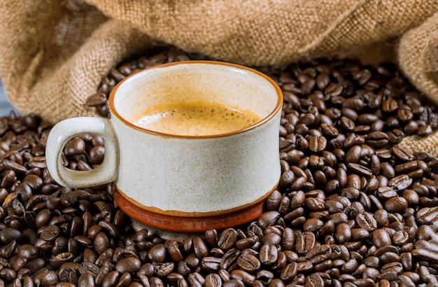 Tasse à café et haricots sur une table en bois.