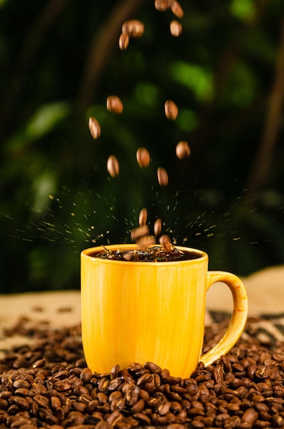 Photo tasse de café jaune avec des grains de café sur la table avec un fond naturel