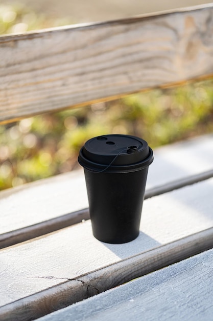 Tasse à café jetable sur banc dans le parc au matin gelé