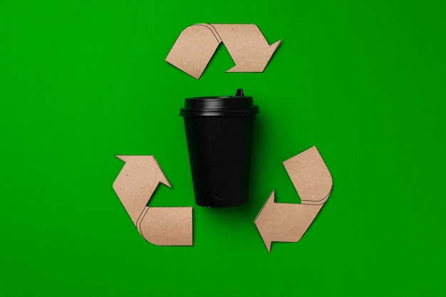 Tasse à café jetable et signe de recyclage sur fond vert