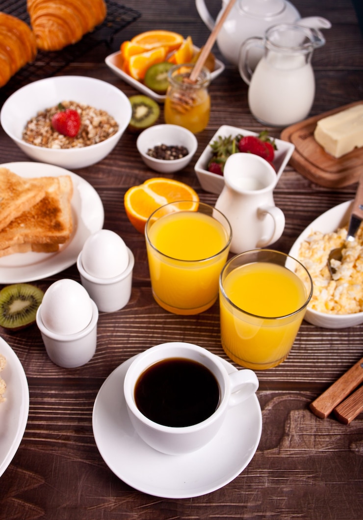 Photo tasse de café, jus d'œufs, fruits et toasts.