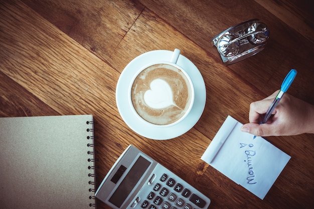 tasse de café latte art forme de coeur avec des outils de bureau sur la table