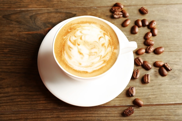 Tasse de café latte art avec des grains sur une surface en bois