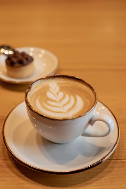 Une tasse de café avec un latte dessus et un petit cookie sur le côté.