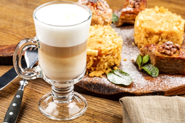 Photo une tasse de café lette mousseuse fraîchement préparée est servie avec un morceau de gâteau sur une table en bois