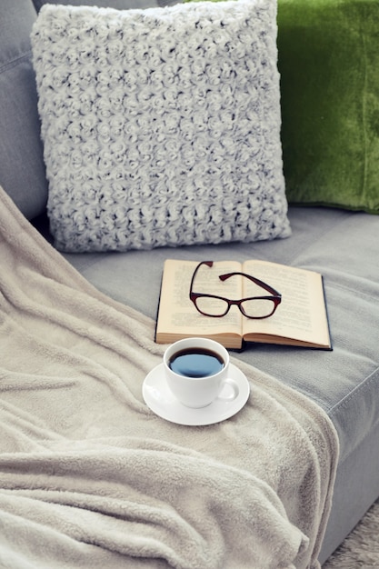 Tasse de café avec livre sur canapé dans la chambre