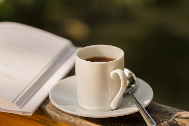 tasse de café et livre ouvert sur table d'extérieur en bois naturel