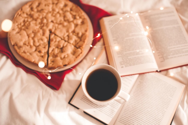 Tasse de café avec des livres ouverts et tarte aux pommes au lit. Bonjour.