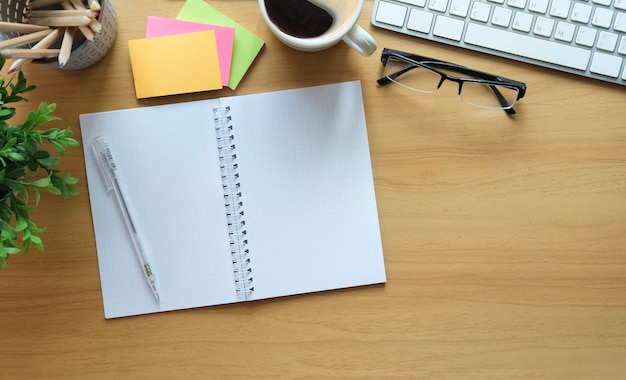 Tasse à café de lunettes de cahier vide et notes autocollantes de couleur sur une table en bois