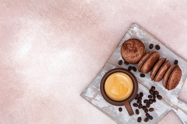 Une tasse de café et des macaroons au chocolat avec des grains de café sur une planche en bois Vue supérieure avec espace de copie