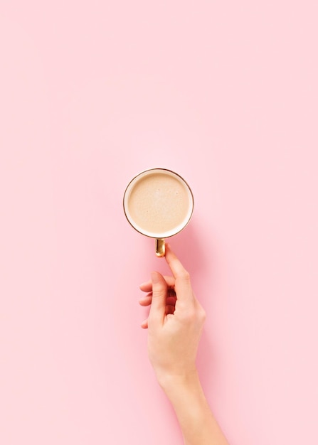 Tasse de café et main de femme sur minimalis pastel rose