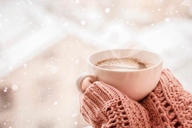 Photo tasse de café à la main sur la fenêtre d'hiver vue d'arrière-plan avec espace de copie de neige