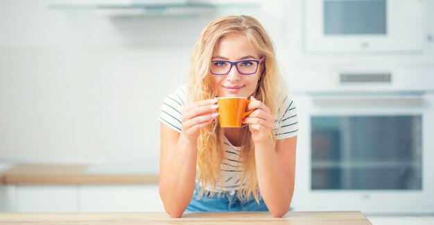 Tasse de café à la main d'une jeune femme heureuse. Jolie fille buvant le thé du matin.