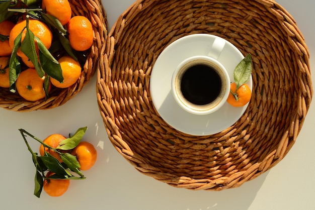 Tasse de café et mandarines vue de dessus Café noir et mandarines dans un panier en osier