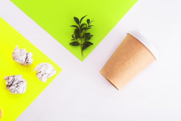 Tasse à café de matériaux réutilisables avec brindille verte et papier croustillant et papier de couleur sur fond blanc