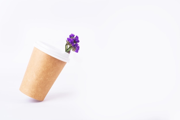 Tasse à café de matériaux réutilisables avec des fleurs bleues à l'intérieur sous un angle par rapport au concept zéro déchet de fond blanc