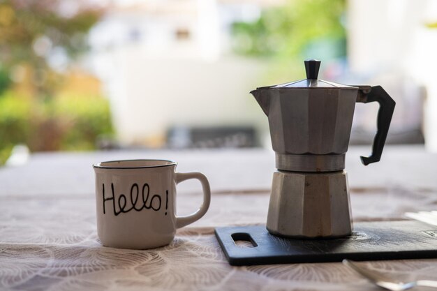 Photo tasse à café avec message qui dit bonjour et cafetière vintage