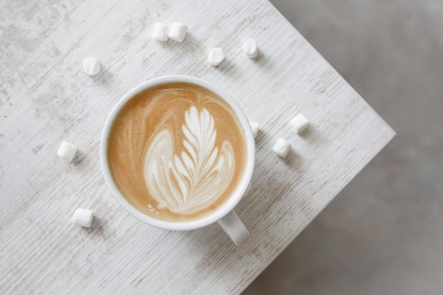 Photo une tasse de café avec un motif de feuilles sur le dessus