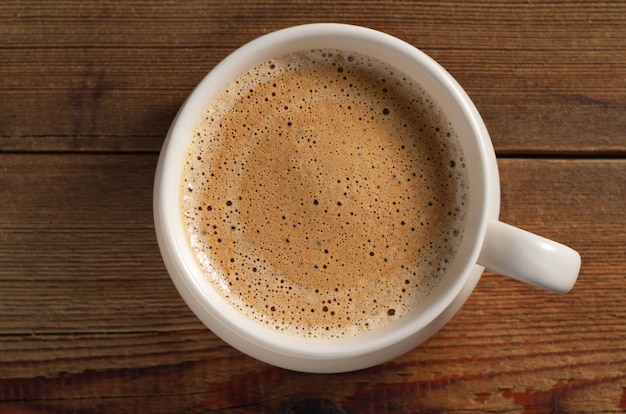 Tasse de café avec de la mousse sur une table en bois