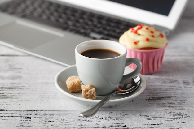 Tasse à café et muffins sur table avec ordinateur