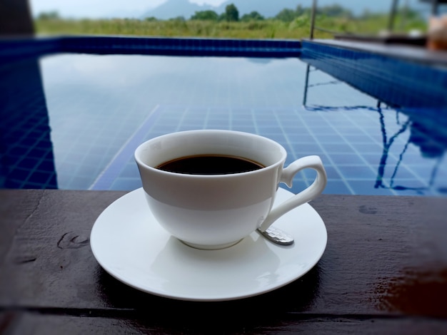 Tasse de café noir chaud bouchent la piscine le matin