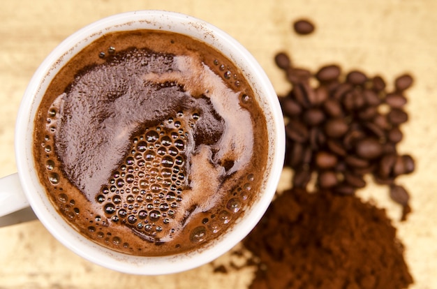 Tasse de café noir chaud frais, haricots et café moulu en arrière-plan flou.