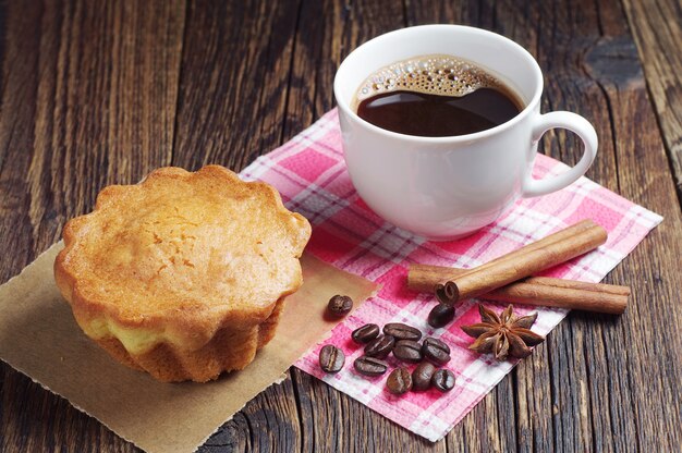 Tasse de café noir et cupcake sucré sur table en bois foncé