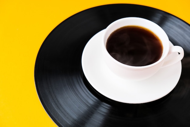 Tasse de café noir sur disque vinyle. Espace de copie. Écouter de la musique. Style rétro. Podcast.