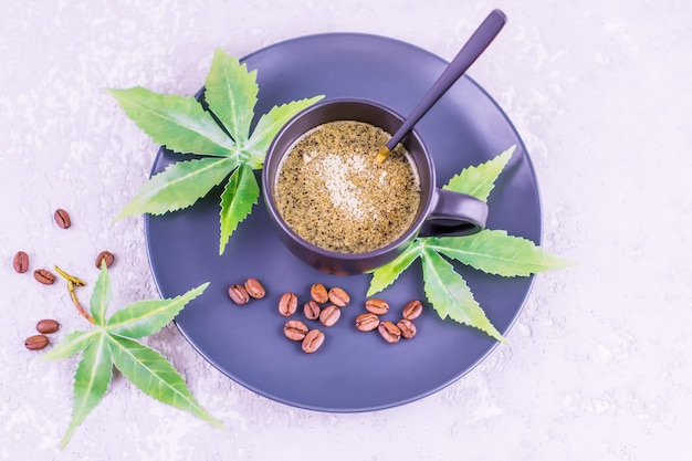 Une tasse de café noir avec du cannabis et des feuilles sur une plaque en céramique. vue de dessus. fond gris.