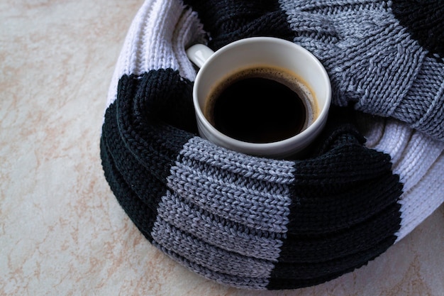 Tasse de café noir enveloppée dans un foulard rayé. Concept de lune d'automne et d'hiver.