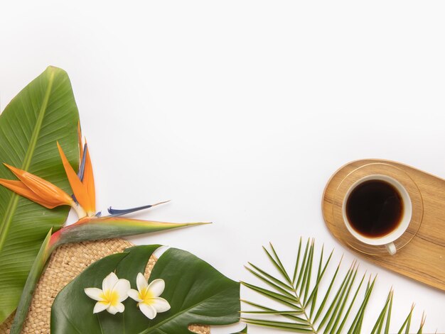 Tasse de café noir avec des feuilles tropicales fraîches