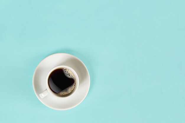 Une tasse de café noir sur fond bleu vue d'en haut