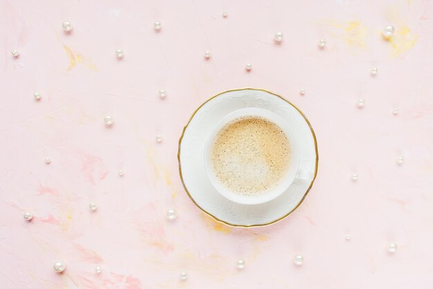 Tasse de café noir sur fond rose avec perles