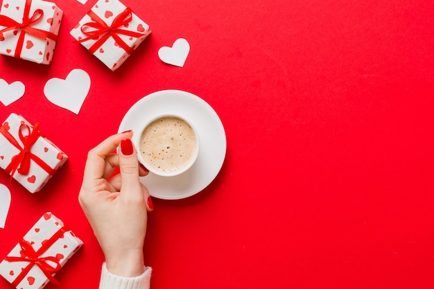 Une tasse de café noir en forme de cœur à plat dans les mains des femmes sur un fond coloré avec une copie de l'espace vue supérieure du jour de la Saint-Valentin et du concept de vacances