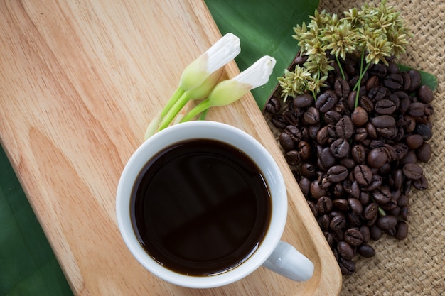 Tasse de café noir et grains de café sur fond en bois.