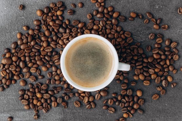 Tasse de café noir avec des haricots sur une table en bois