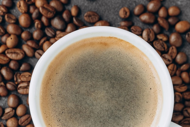 Tasse de café noir avec des haricots sur une table en bois