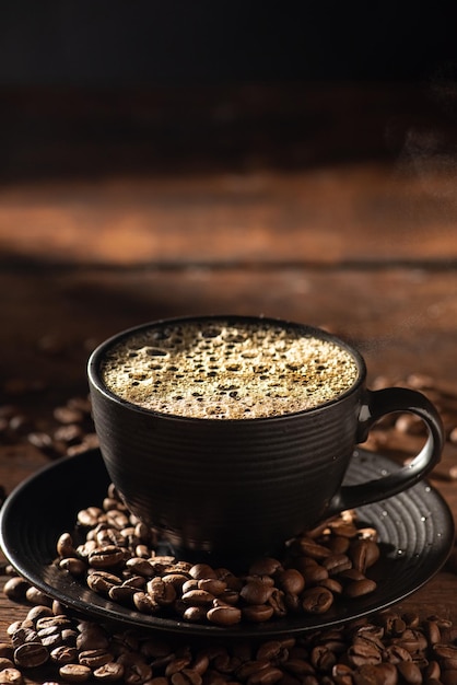 Tasse à café noire avec café chaud et fumée sur bois rustique style alimentaire sombre mise au point sélective photo