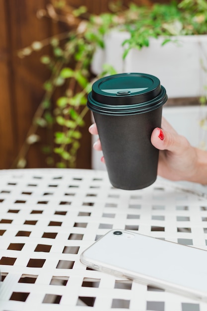 Tasse à café noire dans la main d'une femme