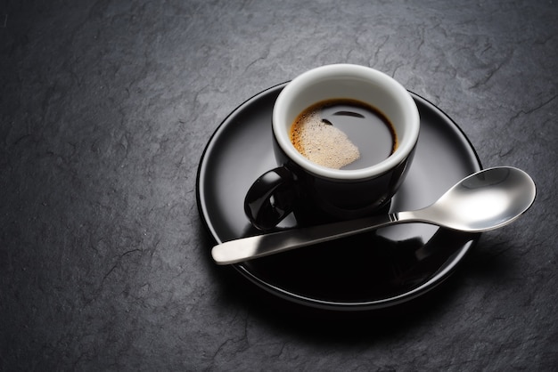 Tasse à café noire sur la texture de fond ardoise sombre