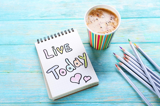 Tasse de café avec note LIVE TODAY et crayons sur fond de bois