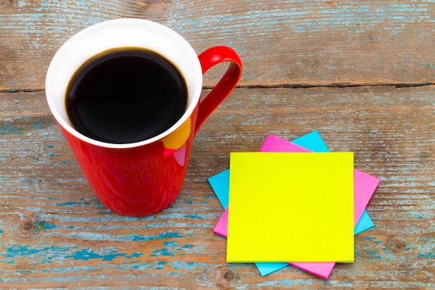 Tasse de café et notes autocollantes avec un espace vide pour un texte sur fond en bois.