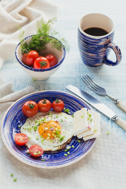Tasse à café, un œuf, du fromage et des tomates cerises pour un petit-déjeuner sain.